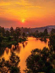 Golden Sunset Over Tranquil Lake with Reflections and Lush Greenery