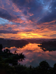Vibrant Sunset Sky Over Calm River Reflecting Landscape Scenery