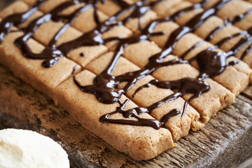 Homemade chocolate bars made of whey protein powder, ground oat flakes, maple syrup, cinnamon and nut butter, closeup