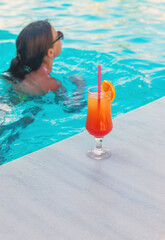 Woman in the pool with a cocktail. Selective focus.