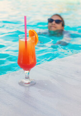 Woman in the pool with a cocktail. Selective focus.