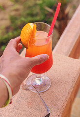 Cocktail in hands of woman against the background of swimming pool. Selective focus.