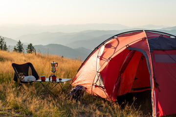 Obraz na płótnie Canvas Remote mountain camping experience showcasing scenic horizon layers, red tent in highland meadow, tranquil nature mood, perfect visual for outdoor sports brands, hiking blogs, lifestyle content