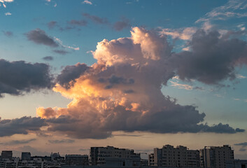 Massive, billowy cumulus clouds fill the sky above a sprawling cityscape in Hangzhou