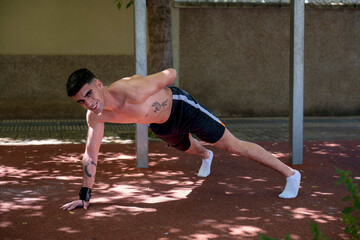 Shirtless athlete doing calisthenics push ups in park