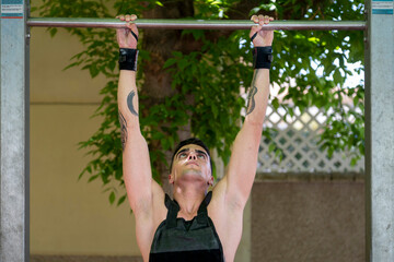 Determined male athlete performing pull ups on outdoor gym bar during calisthenics workout