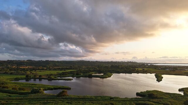 Hyperlapse aerial drone footage at sunset over the bird nature reserve in Guiss&eacute;ny, Porz Olier, Brittany, France. The Atlantic Ocean coastline reveals protected wetlands, tidal flats, and peaceful coa