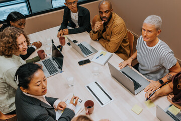 High angle view of male and female business professionals discussing strategies with each other in meeting room at office