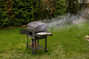 mały grill węglowy podczas rozpalania, kłęby dymu 