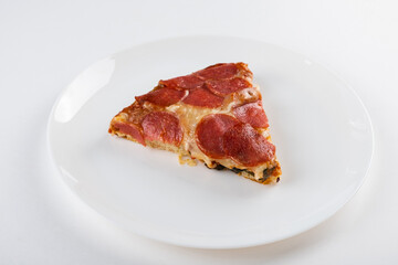 Slice of pepperoni pizza on a white plate, showcasing melted cheese and crispy crust, highlighting delicious toppings and inviting presentation for food enthusiasts