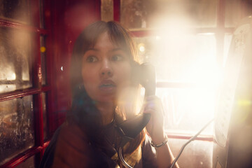 Scared girl calling 911 from telephone booth