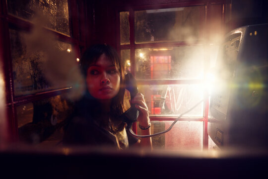 Worried girl talking on phone while hiding in booth