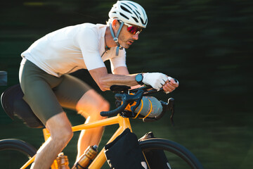 Radfahrer fährt auf gelben Fahrrad und Gepäck auf der Strasse in den Sonnenuntergang, bikpacking, Radreise