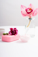 cosmetic cream, soap and bath salt with pink flower, white wood table
