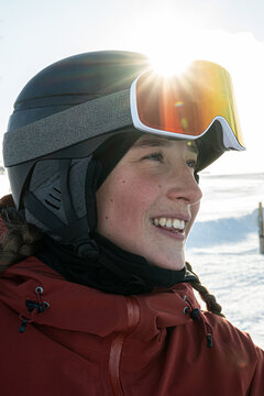 Sun shining on smiling teenage girl wearing skiing helmet and googles