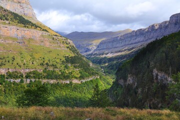 Naklejka premium Mountain valley in cloudy Spanish Pyrenees. Viewed from Senda de Los Cazadores hiking trail in Ordesa y Monte Perdido National Park in Pyrenees.