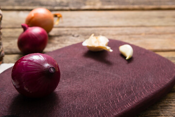 onions and garlics on cutting board, weathered wooden background
