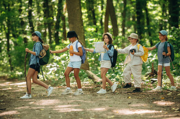 Fototapeta premium Trusting the girl with a map. Group of children in the forest on a hike