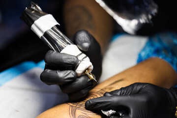 Tattoo artist is concentrated on his work. Closeup.