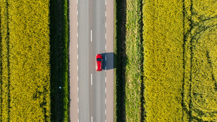 Aerial view of car moving on country road amidst field