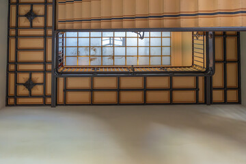 A decorative staircase viewed upward reveals geometric ceiling patterns. A large frosted skylight diffuses natural light.