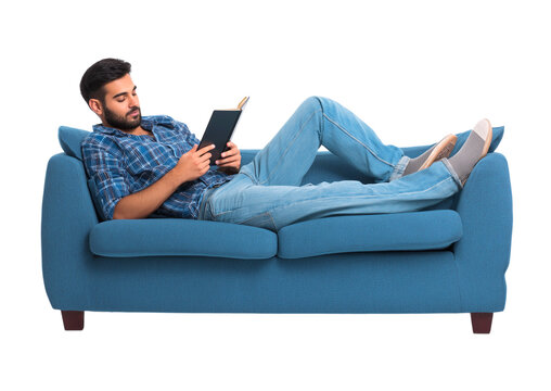 Young Man Relaxing on a Blue Sofa, Engaged in Reading a Book Comfortably isolated on a transparent background