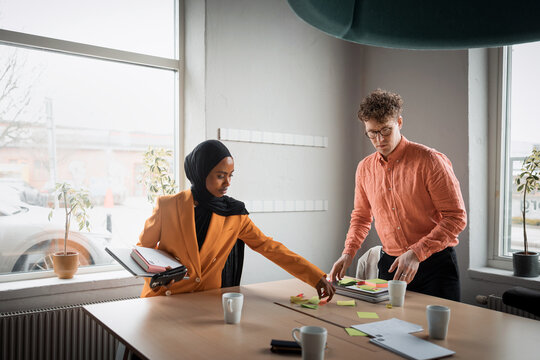 Male and female business employee winding up after meeting in office