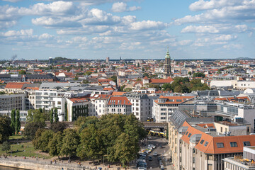 Obraz premium A view over the rooftops of Berlin with many historical buildings and a green park in the foreground. The city stretches to the horizon.
