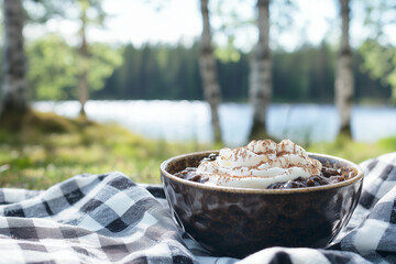 Traditional mammi with cream served outdoors by lake in summer picnic setting