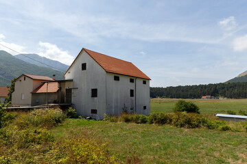 Obraz premium Houses with a red-tiled roof situated in a rural field with distant mountains