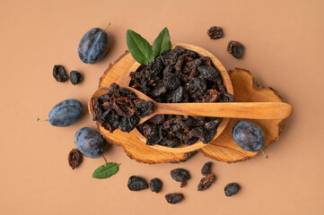 Dried plum prunes in wooden spoon and bowl, fresh plums on brown background. Dried fruit, sweet tasty healthy pitted natural dessert flat lay top view. Food background