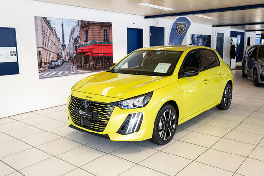 Safenwil, Switzerland, August 16, 2025. New Peugeot 208 small car exterior view. Emil Frey open days showroom floor, wide angle view, window light