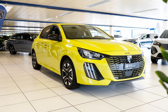Safenwil, Switzerland, August 16, 2025. New Peugeot 208 small car exterior view. Emil Frey open days showroom floor, wide angle view, window light