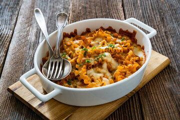 Pasta casserole with marinara sauce and mozzarella cheese on wooden table