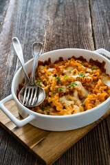 Pasta casserole with marinara sauce and mozzarella cheese on wooden table