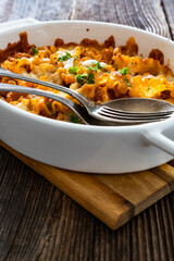 Pasta casserole with marinara sauce and mozzarella cheese on wooden table