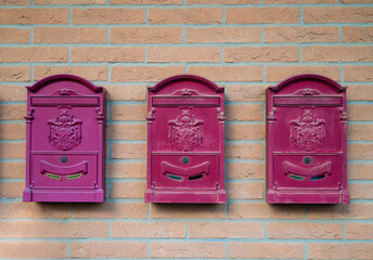 Pink  metal postcard mailboxes  on brick wall 