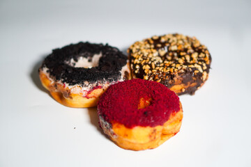 Three donuts with different flavors and toppings on a white background
