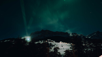 Green aurora borealis dancing above snowy alpine hills under starry sky, long exposure night...