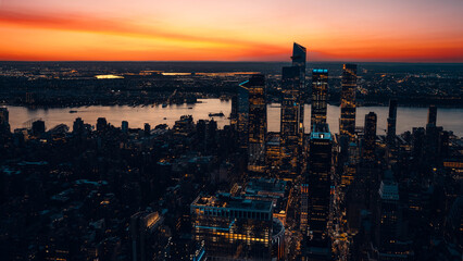 Fototapeta premium Lower Manhattan skyline at sunset seen from Brooklyn with glowing skyscrapers and river reflections, HDR