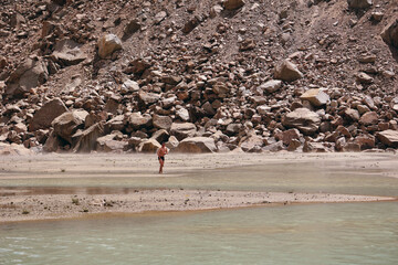 A man on the shore of a lake in the mountains is going to swim. A lake in the mountains surrounded by rocks, Kyrgyzstan, Tien Shan