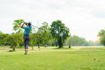 Asian man enjoying the morning round of golf in soft and warm sunlight.