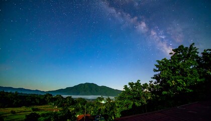 Night sky panorama showcasing the Milky Way galaxy above a tranquil landscape of mountains, trees, and a valley