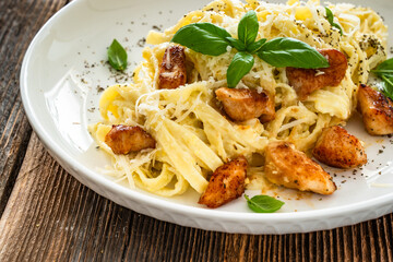 Classic creamy chicken alfredo fettuccine pasta on wooden table	