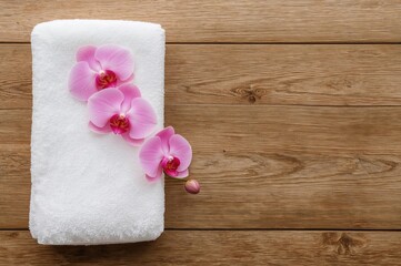 Wooden surface adorned with orchid blossoms and a towel, space available for text