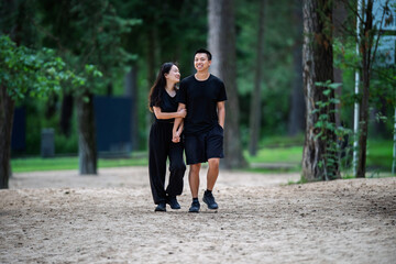 Obraz premium Young 20's Chinese Asian Couple Smiling While Enjoying a Walk Through the Forest Park