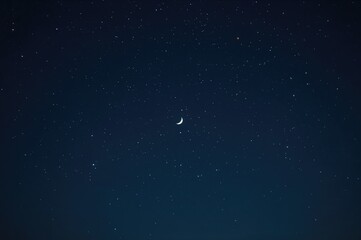 Fototapeta premium Village under the dark night sky with a crescent moon and starry backdrop, symbolizing religious themes and Ramadan.