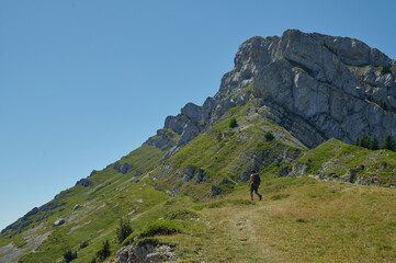 Lone hiker walking on alpine trail in Vercors Massif French Alps