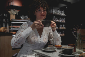 Bride in a lace dress enjoying coffee at a cozy cafe with an elegant atmosphere.   Love, relationships, happiness, urban concept. 
