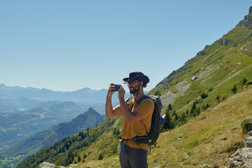 Hiker taking smartphone photo in Vercors Massif French Alps mountain landscape